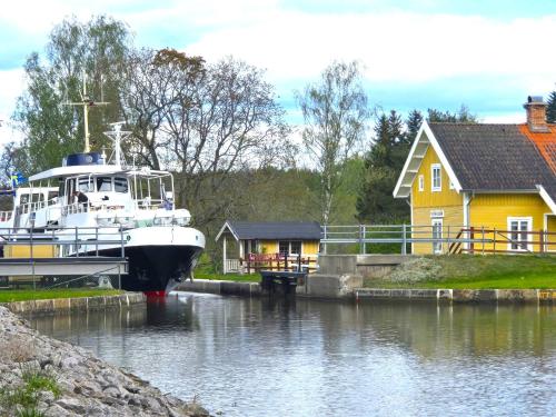 a boat docked in the water next to a yellow house at Norrqvarn Hotel & Resort by Vänerport in Lyrestad