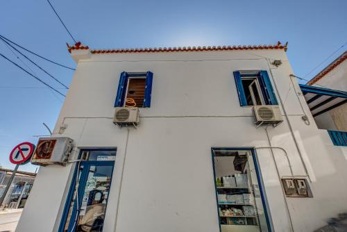 a white building with blue windows on a street at Andy Port House with Seaview by Goutos Properties in Ermioni