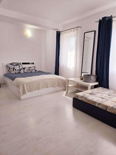 a white bedroom with two beds and a mirror at Oaza de Verdeata in Vama Veche
