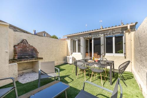 un patio avec une table et des chaises sur l'herbe dans l'établissement Le Patio - Spacieux T3 avec climatisation et jardin privatif, à Bergerac
