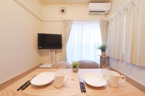 a dining room table with white plates and a tv at Full House Rent in Tokyo, Ghibli, Sakura, Shinjuku 1H in Higashi-murayama