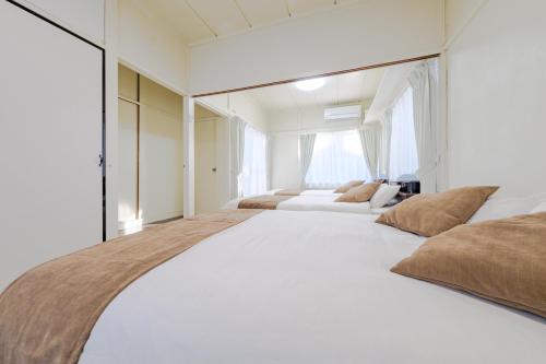a white bedroom with two beds and a window at Full House Rent in Tokyo, Ghibli, Sakura, Shinjuku 1H in Higashi-murayama