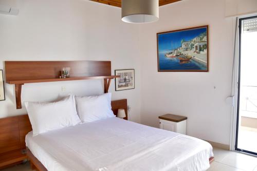 a bedroom with a bed with white sheets and a window at Deep Blue Apartments in Karpathos