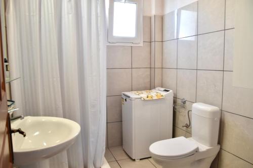a white bathroom with a toilet and a sink at Deep Blue Apartments in Karpathos