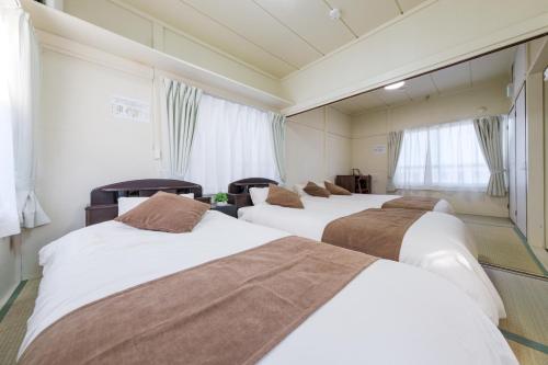 una fila de tres camas en una habitación de hotel en Full House Rent in Tokyo Ghibli Sakura Shinjuku 1H, en Higashi-murayama