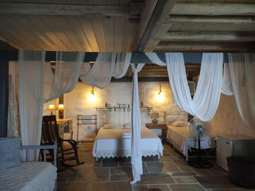 a bedroom with two beds with white drapes at Stone house 1883 Kymi with pool in Enoría