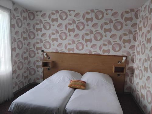a bedroom with two beds with white sheets and a pillow at Hôtel de Tessé in Bagnoles de l'Orne