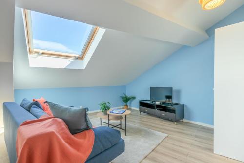 a living room with a blue couch and a tv at Le Travi - Studio climatisé au centre de Bergerac in Bergerac