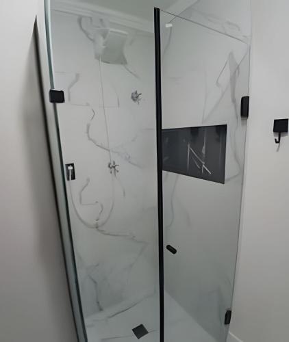 a glass shower door with white marble at SHB - The Jewel Pitangueiras with complete leisure in Guarujá