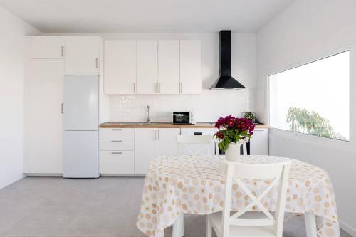 eine weiße Küche mit einem Tisch und einer Vase aus Blumen in der Unterkunft Sunset Horizon Hideaway & Terrace, Santa Úrsula in Santa Úrsula