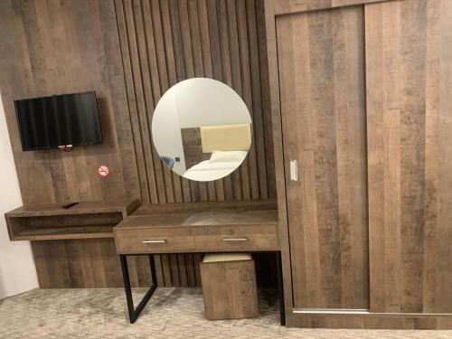 a bathroom with a vanity with a mirror and a tv at اعالي للشقق المخدومه in Abha