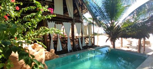 a swimming pool in front of a house with palm trees at Swahili Palace Zanzibar in Pwani Mchangani