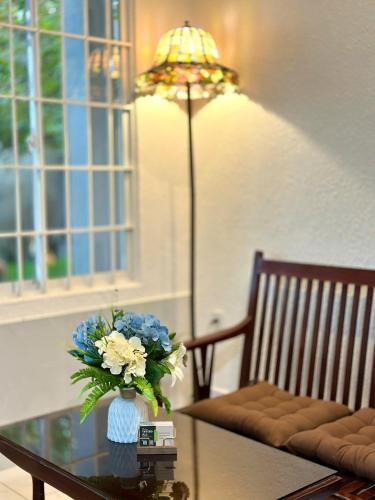 a vase of flowers on a table next to a lamp at Tiami Eden Villa - Nghỉ Dưỡng Sân Vườn Ven Biển in Vung Tau
