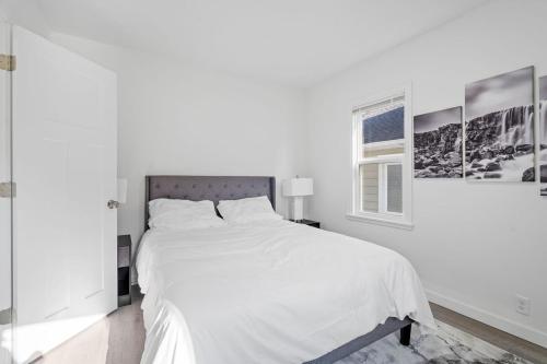 a white bedroom with a white bed and a window at Movie Game Room & Fire Pit Luxury Spacious Home in Minneapolis