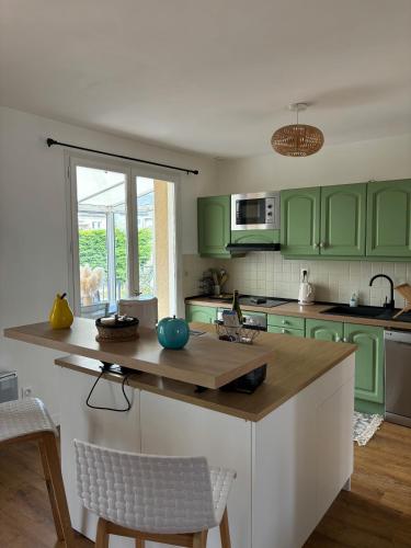 une cuisine avec des placards verts et un comptoir en bois dans l'établissement Les Mimosas - Jardin clos, à La Richardais