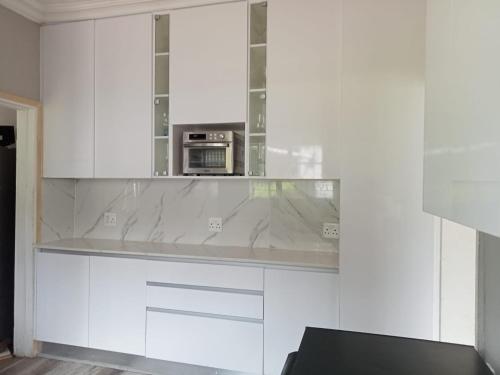 a kitchen with white cabinets and a microwave at 60 ON Kennington in East London