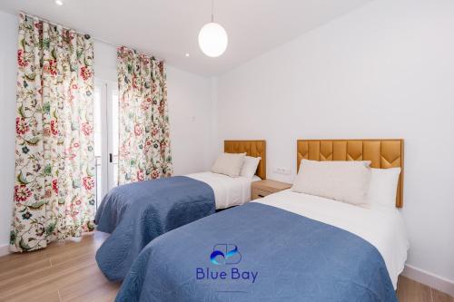 Dos camas en una habitación con el logo de Blue Bay. en La Soleá Historic Center, en La Herradura