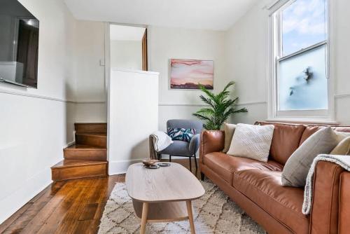 a living room with a brown couch and a table at Hobart Heritage Home - Close to CBD & Airport in New Town
