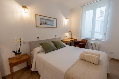 a bedroom with a large white bed and a window at Suite Haus Castelar in Santander