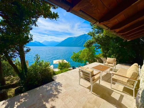 a patio with a table and chairs and a view of a lake at Villa Sunset, Dobrota in Dobrota