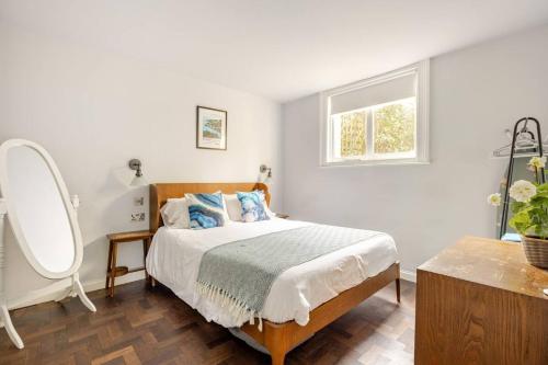 Un dormitorio con una cama con espejo y una ventana. en Classroom Flat Suite in a converted school in Fowey town centre, en Fowey