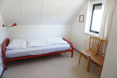 a bed in a room with a chair and a window at Kustverhuur, Park Schoneveld Stern 263 in Breskens