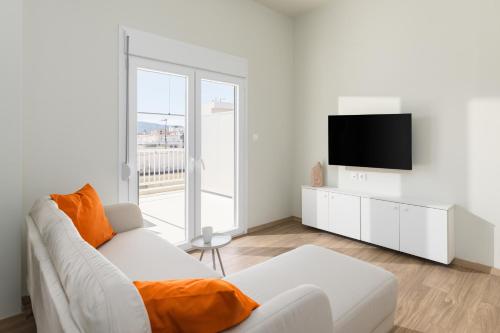 a white living room with a white couch and a tv at Celine Volos by halu! Cozy apartments in the center in Volos