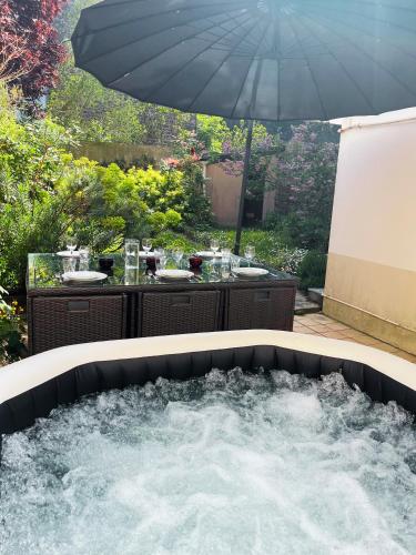 a hot tub with an umbrella in a backyard at IDEAL - Plage, jardin & jacuzzi, proche plage et thalasso - 1 à 6 personnes in Saint Malo