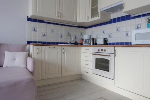 a kitchen with white cabinets and blue tiles at Flatbook - City Center SPA Apartments 6B,C in Gdańsk