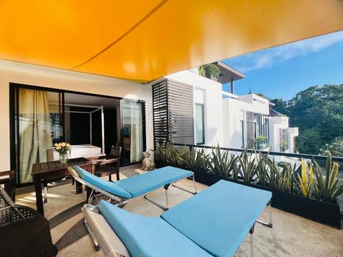 a balcony with blue chairs and a bed on it at Naiharn Pool Villa Number 5 in Rawai Beach