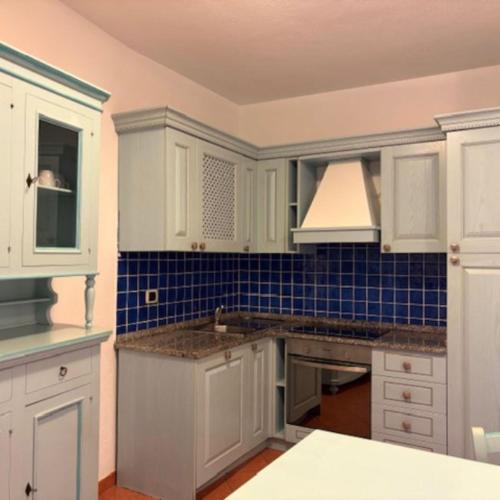 a kitchen with white cabinets and blue tiles at Marinella Residence in Santa Marinella
