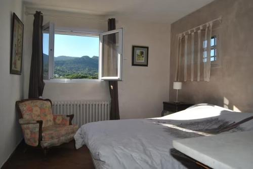 une chambre avec un lit, une chaise et une fenêtre dans l'établissement Mas de la Haumière, au Plan-de-la-Tour