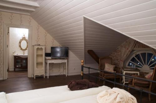 a bedroom with a bed and a staircase with a television at Liepupe Manor in Liepupe