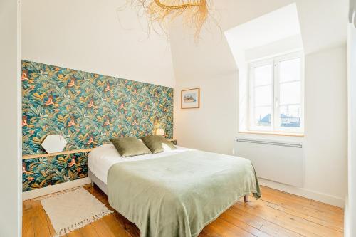 - une chambre avec un lit orné d'un mur fleuri dans l'établissement Emeraude - Superbe t2 lumineux - refait à neuf, à Dinard