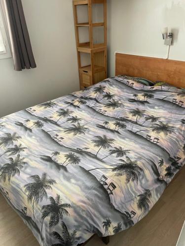 Una cama con una manta con palmeras. en Mobilhome, en Louannec
