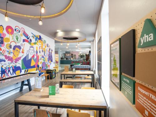 a restaurant with tables and chairs and a colorful wall at YHA Manchester in Manchester