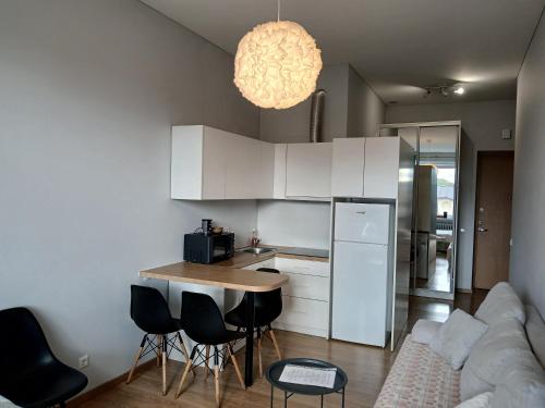 una cucina con mobili bianchi, tavolo e sedie di Studija Kauno centre a Kaunas
