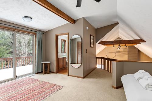 a living room with a vaulted ceiling and a large window at Majestic Escapes Hot Tub Firepit Deck Large Yard in Lake Ann