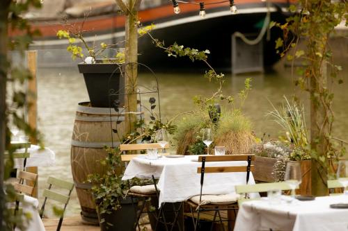 a table with white linen and chairs and a boat at FLOATS by H2OTEL Rotterdam in Rotterdam