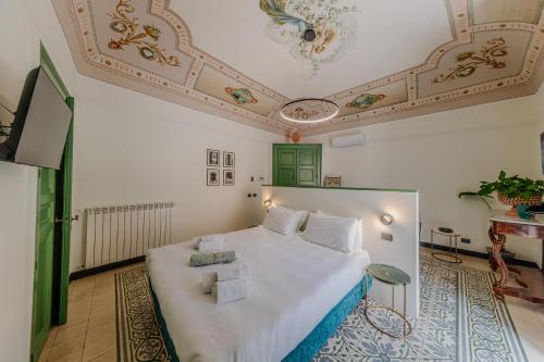 a bedroom with a large white bed with a ceiling at Palazzo Villelmi in Cefalù