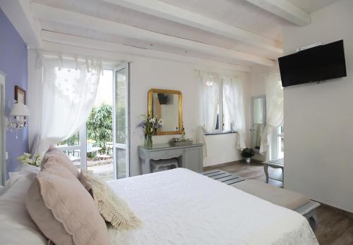 a white bedroom with a large bed and a mirror at Villa Valentina in Levanto