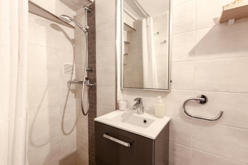 une salle de bain blanche avec un lavabo et une douche dans l'établissement Appartement Hanou de 1 à 4 personne, à Bandol