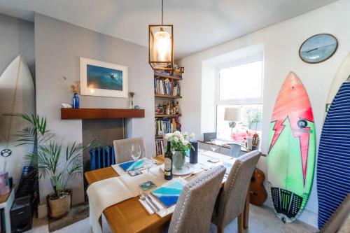 a dining room with a table and surfboards at Palm Haven House - Luxury family-friendly Newquay surf house near Porth Beach perfect for walking, pets, exploring in Newquay