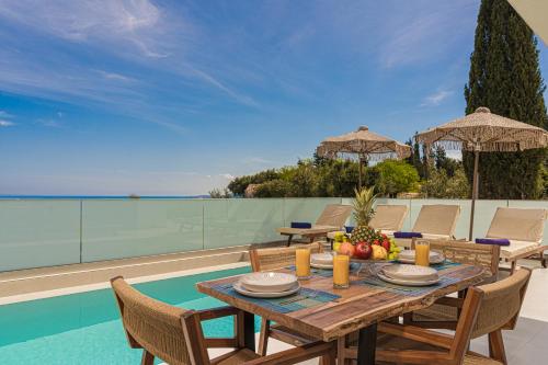 a table and chairs on a patio with a view of the ocean at Jasmina Villas in Agios Nikolaos