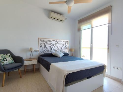 Un dormitorio con una cama y una silla y una ventana. en Casa Helios - Precioso ático con sol, mar y relax, en Aguadulce