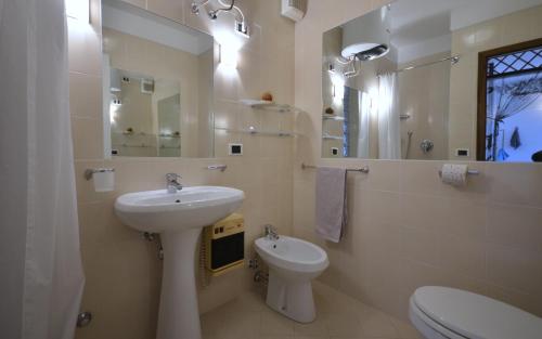 a white bathroom with a sink and a toilet at Appartamenti La Quercia in Bibione