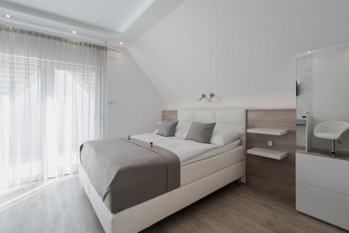 a white bedroom with a large bed and a window at Residence Malva in Valtice