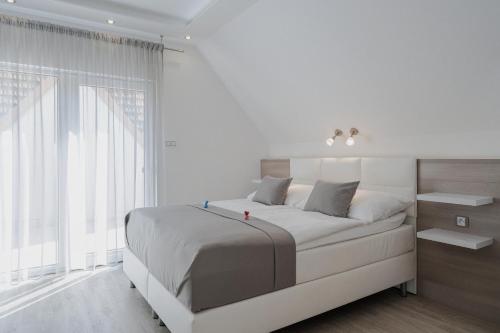 a white bedroom with a large bed and a window at Residence Malva in Valtice