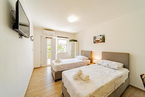 a room with two beds and a television in it at Rooms & Apartments Mirakul in Vela Luka
