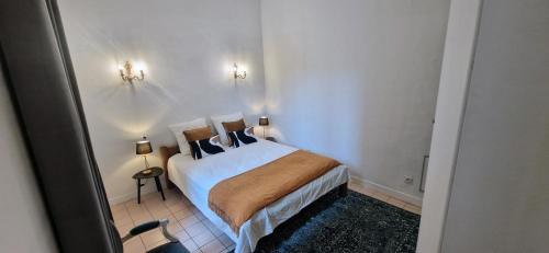 a bedroom with a bed and two lights on the wall at LE PARC2 Appartement Authentique, Coeur de Ville, Proximité Parking, Climatisé in Sète
